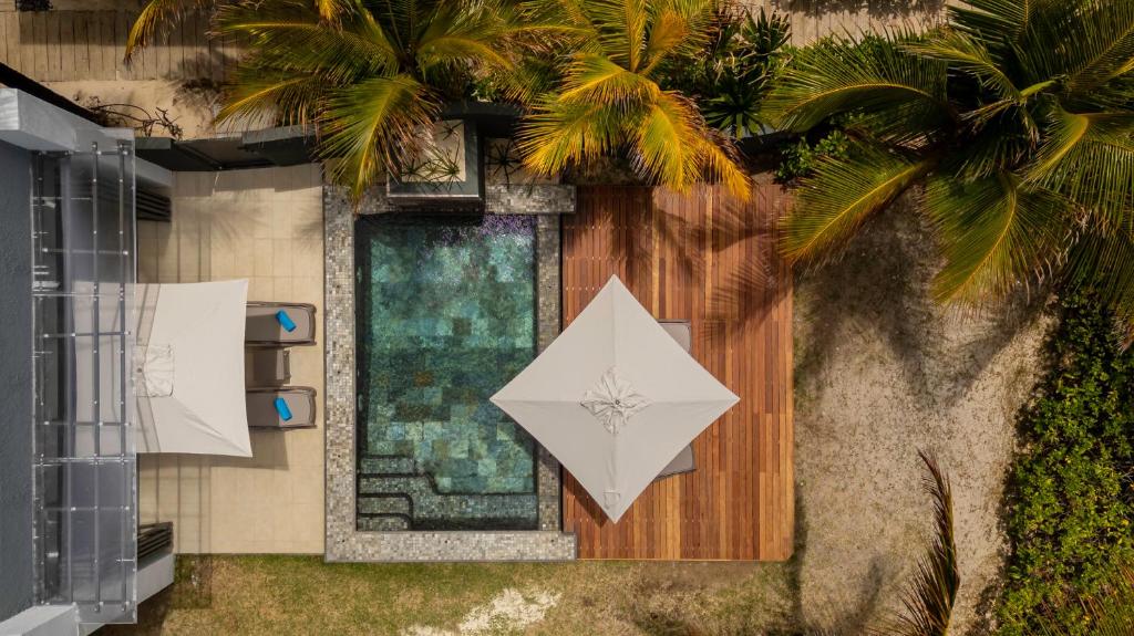 a building with a palm tree and a white umbrella at Stylia Villas in Trou dʼ Eau Douce