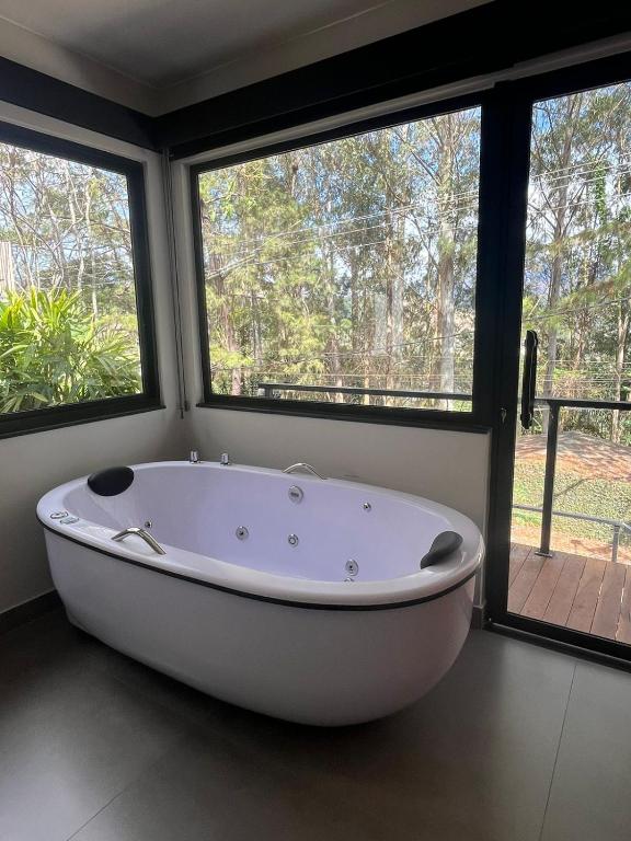 a large white bath tub in a room with windows at Villa Nogueira in Araras Petropolis