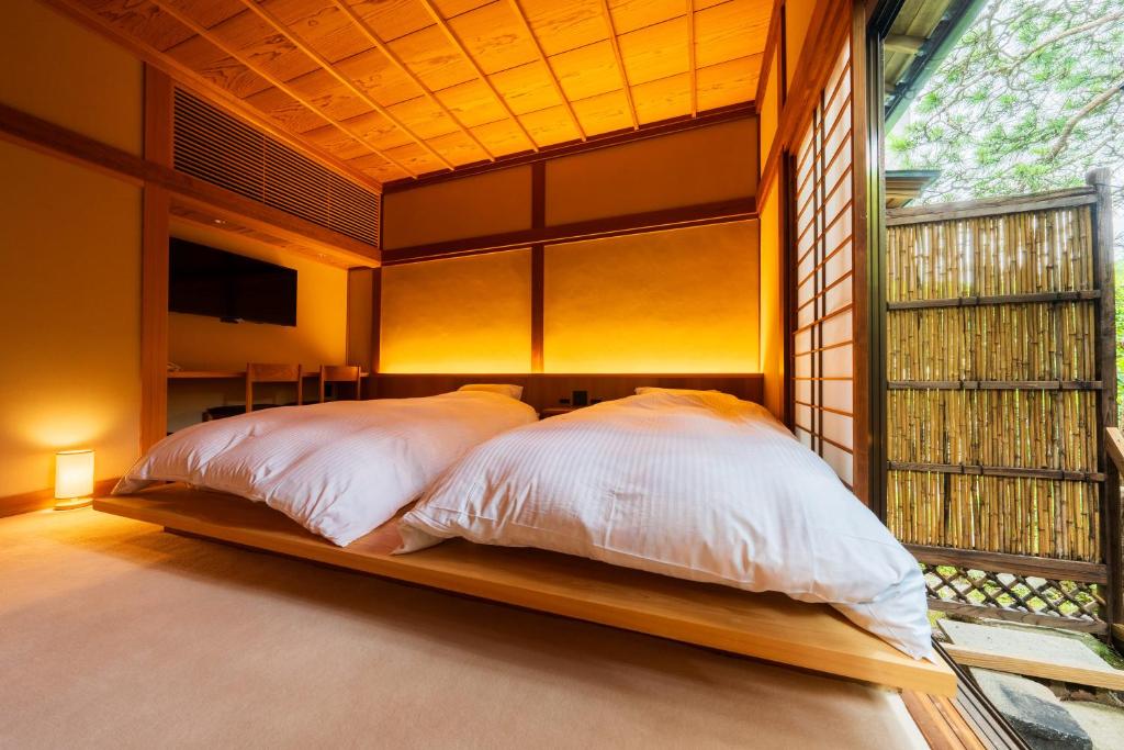 a bedroom with a bed in a room with a window at Kappo Ryokan Yumesaki in Beppu