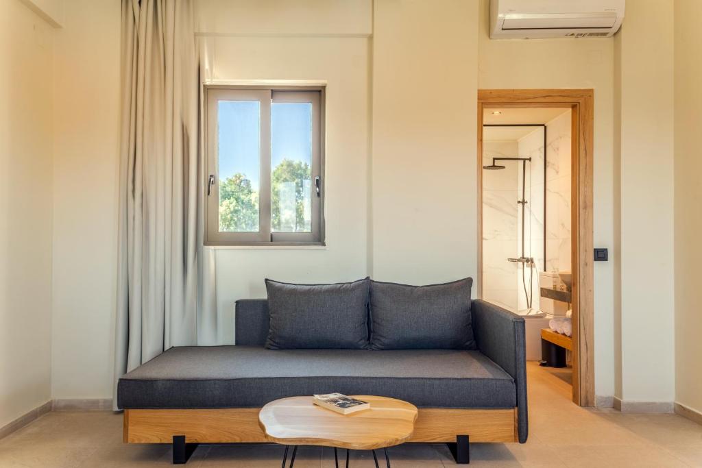 a couch in a room with a window and a table at Malena Hotel & Suites - Adults Only by Omilos Hotels in Amoudara Herakliou
