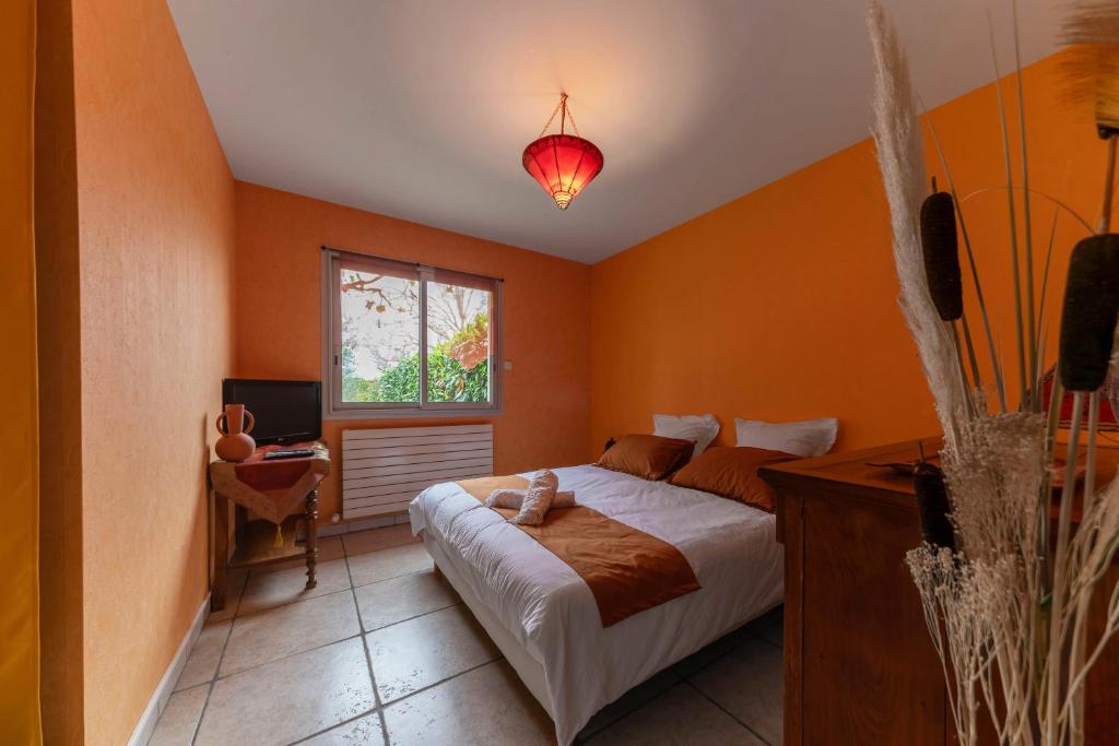 a bedroom with orange walls and a bed and a window at La Petite Maison Gannat in Gannat