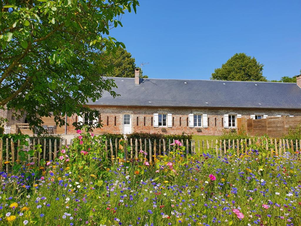 an old brick house with a garden of flowers at La Bergerie in Saigneville