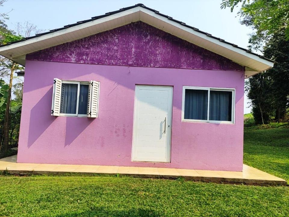 a pink house with a white door and windows at Casa mobiliada privativa in Caiçara