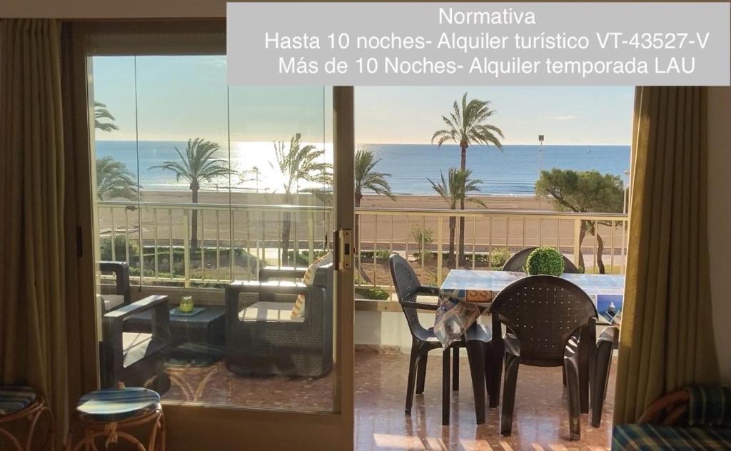 a room with a table and chairs and a view of the ocean at Apartamento en la playa Arensol Cullera in Cullera
