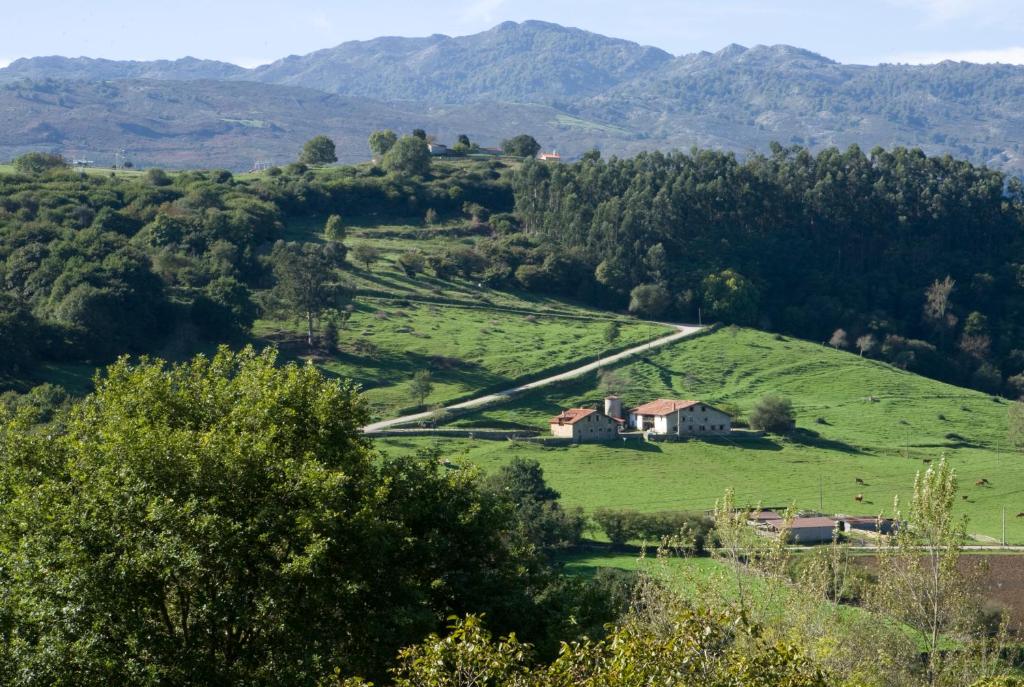 a farm on a hill with mountains in the background at Primorías Camijanes in Camijanes