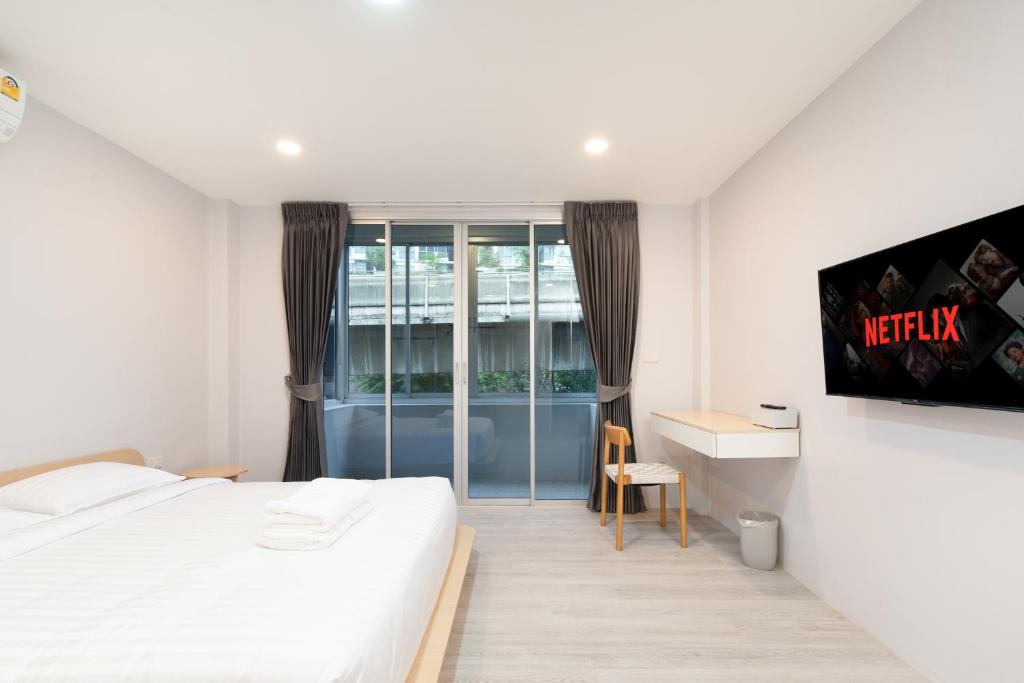 a bedroom with a bed and a desk and a tv at Wash House Chatuchak in Bangkok