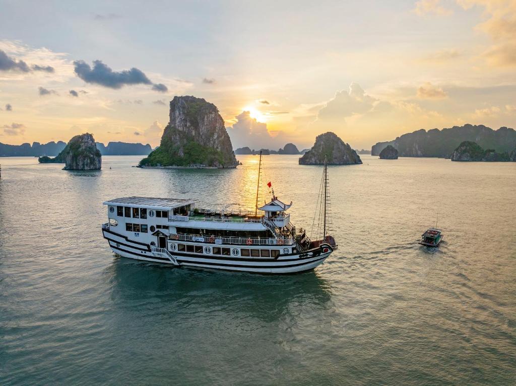 un barco en el agua con montañas en el fondo en Renea Boutique Cruise, en Ha Long