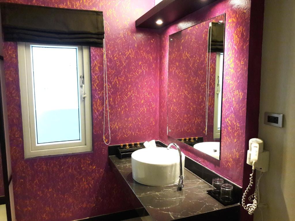A vivid purple bathroom vanity with a vessel sink, mirror and frosted window.