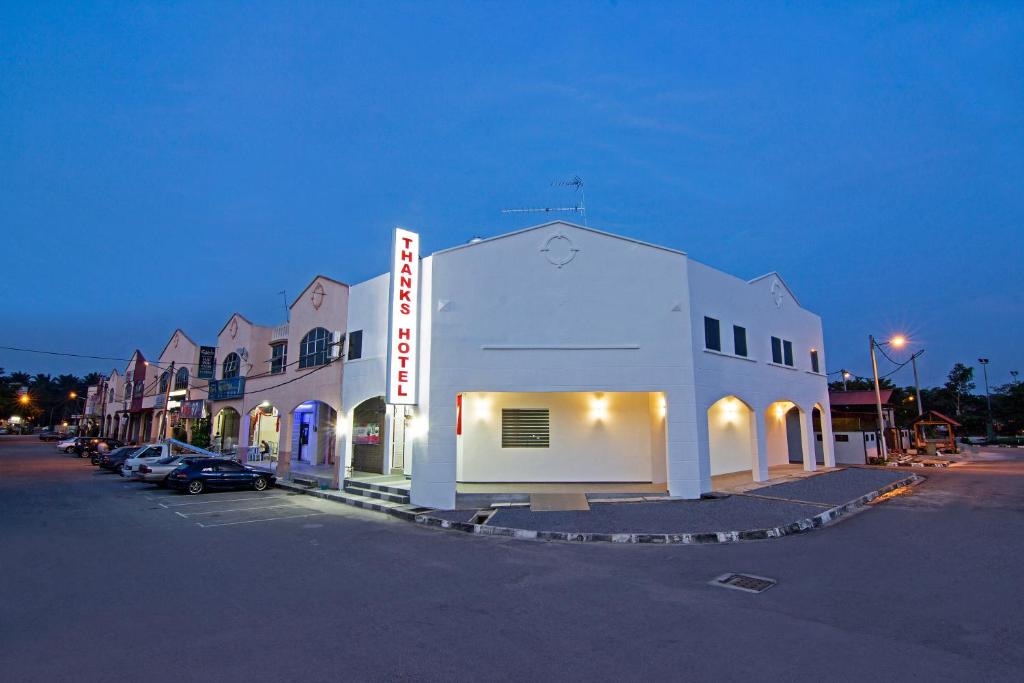 a large white building in a parking lot at night at Thanks Hotel in Parit Buntar