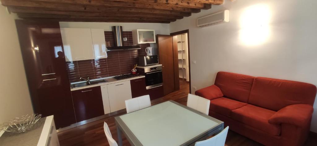 Una sala de estar con un sofá rojo y una cocina. en CA' Botteri, en Venecia
