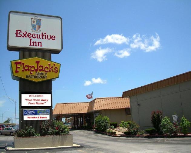 a sign for an expensive inn in a parking lot at Executive Inn and Suites Springdale in Springdale