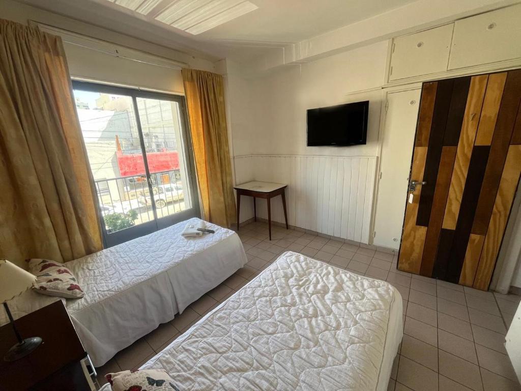 a hotel room with two beds and a window at Hotel Urbano Ventia in Comodoro Rivadavia