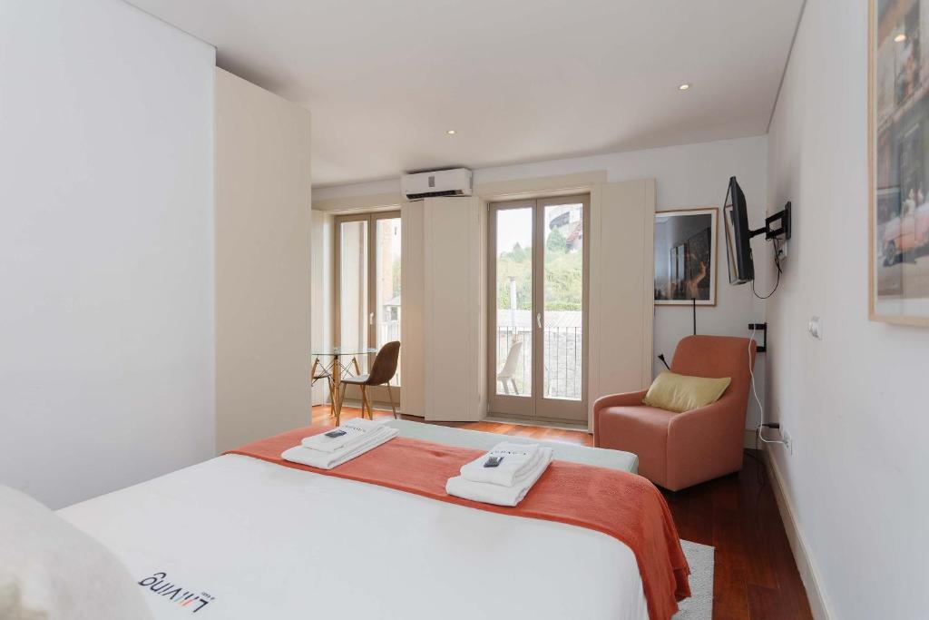 een slaapkamer met een groot wit bed en een stoel bij Liiiving in Porto - Trindade Deluxe Studios in Porto