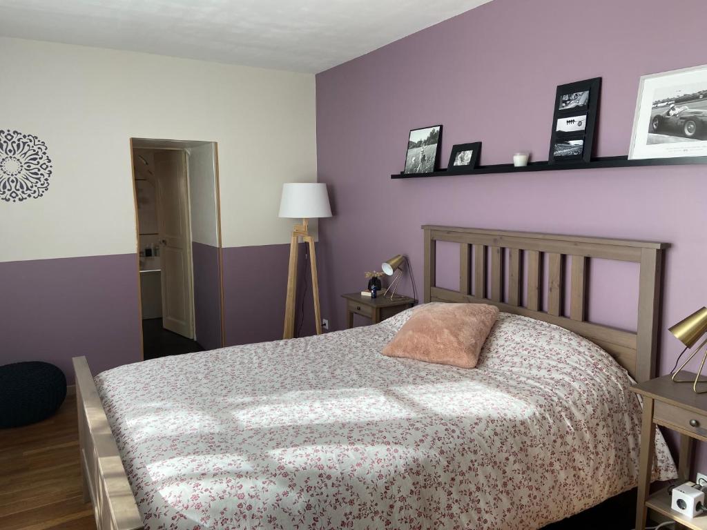 a bedroom with a bed and purple walls at Les chambres de l'atelier in Marigné-Laillé