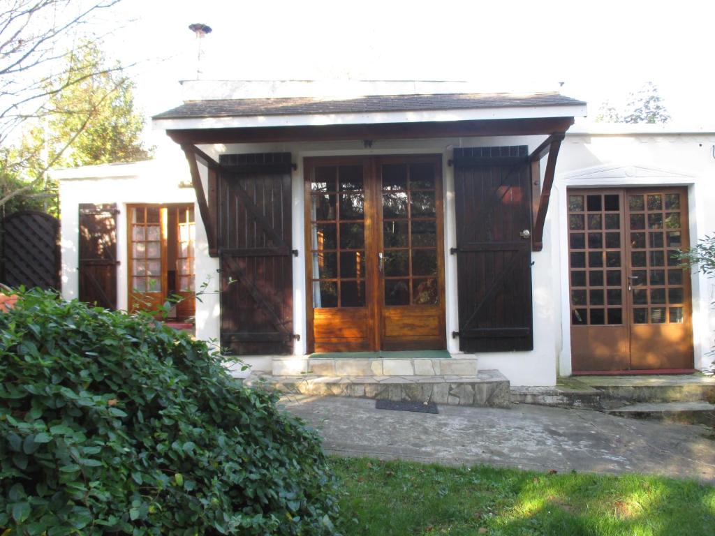 une porte d'entrée d'une maison blanche avec des portes en bois dans l'établissement Gîte Habas, à Habas