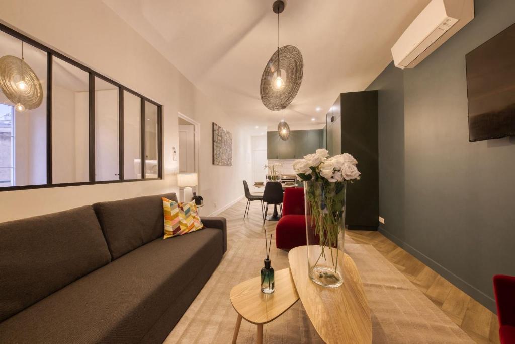 un salon avec un canapé et une table avec des fleurs dans l'établissement Moderne & Spacieux - Terrasse Privée - Parking Gratuit - 6 Pers, à Montreuil