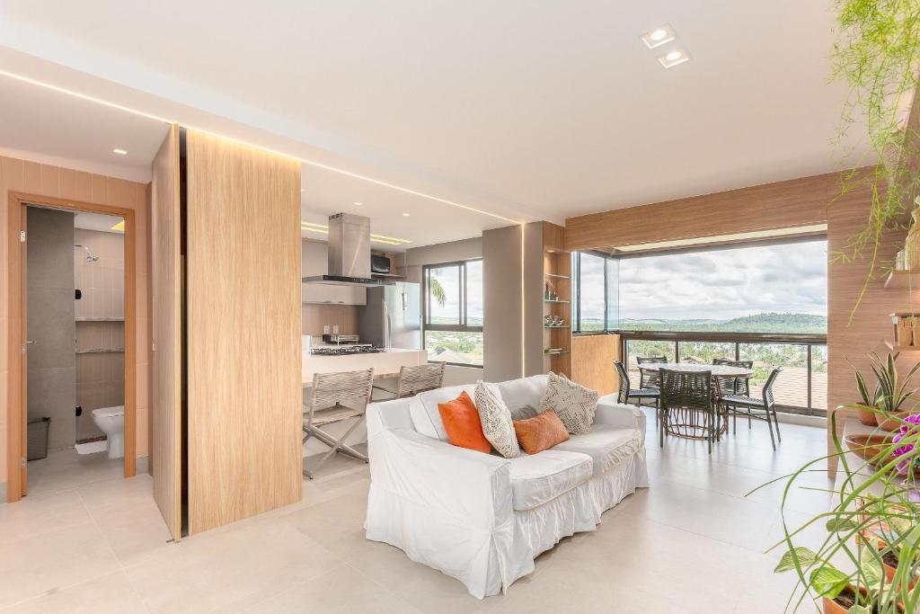 a living room with a white couch and a kitchen at Eco Resort Praia dos Carneiros Apt Luxo Beira Mar in Praia dos Carneiros