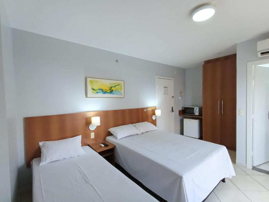 a hotel room with two beds with white sheets at Flat com parque aquático in Caldas Novas