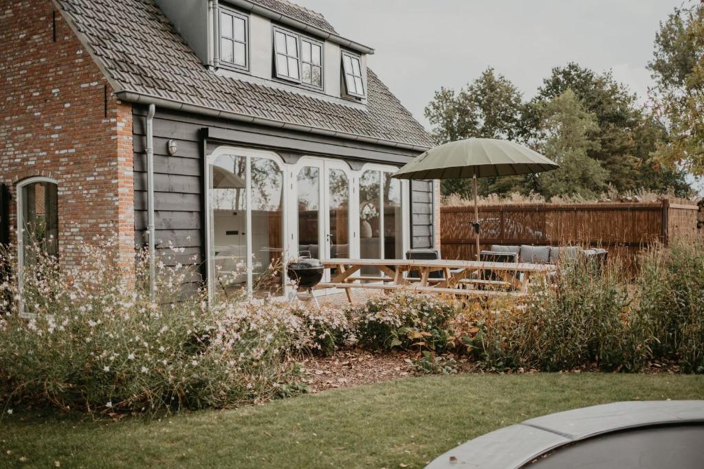 una casa con mesa y sombrilla en NIEUW Landelijk vakantiehuis aan zee, en Oostkapelle