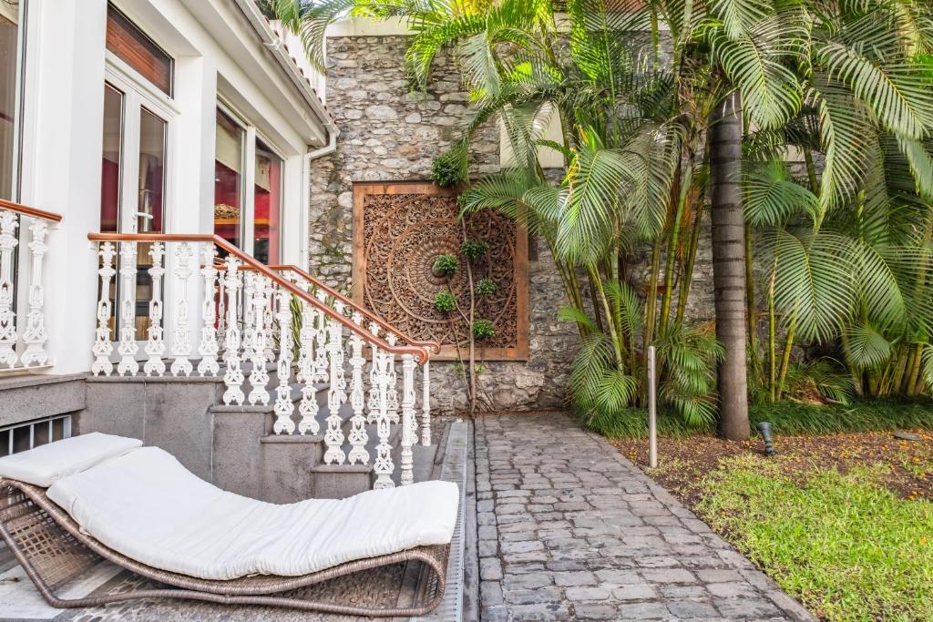 eine Veranda mit einem Stuhl und Palmen in der Unterkunft Villa Diniz by Madeira Dream Stays in Funchal