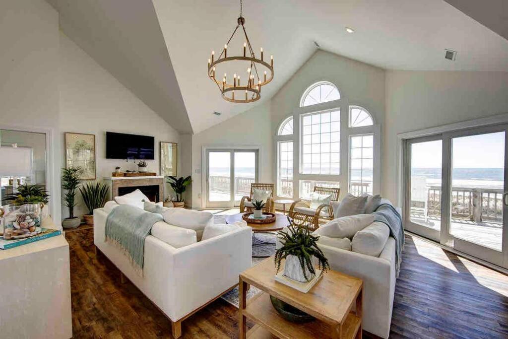 a living room with white furniture and a chandelier at 8 Bed Oceanfront in OBX with Pool & Hot Tub in Frisco