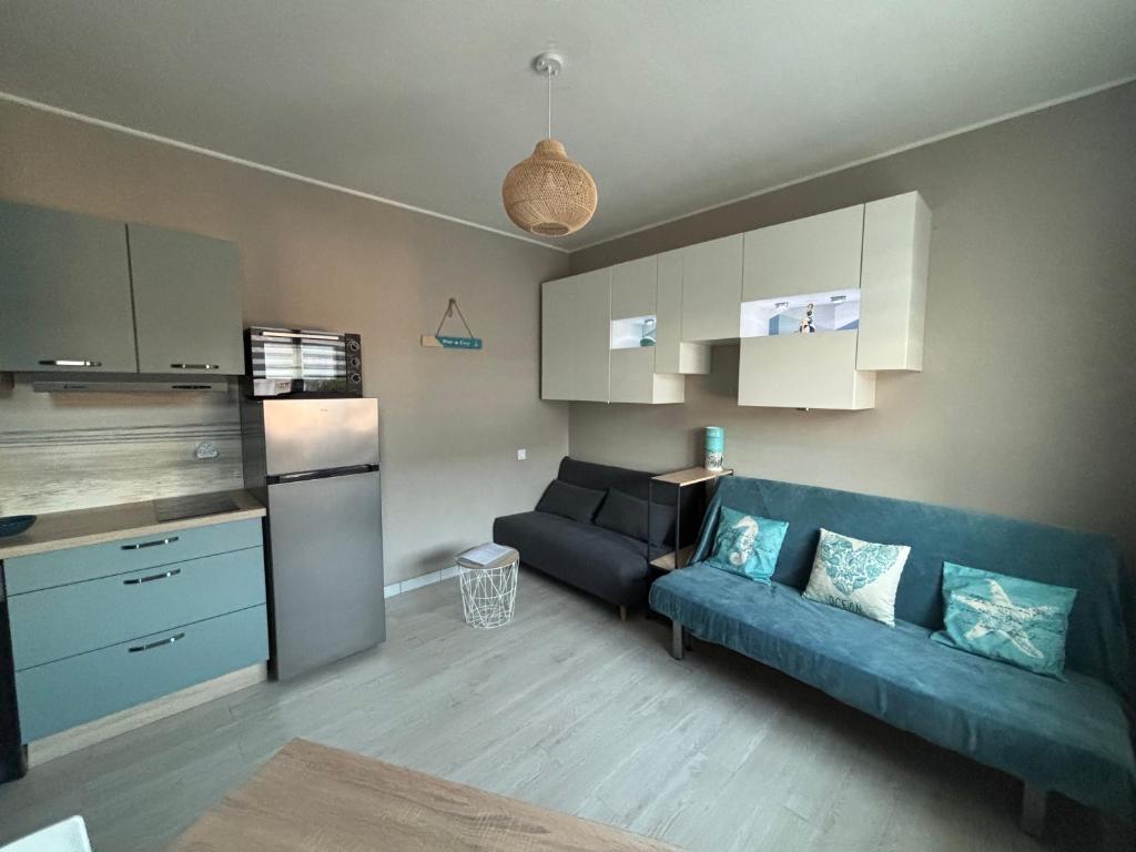 un salon avec un canapé bleu et une cuisine dans l'établissement Studio 300m de la plage, à Royan