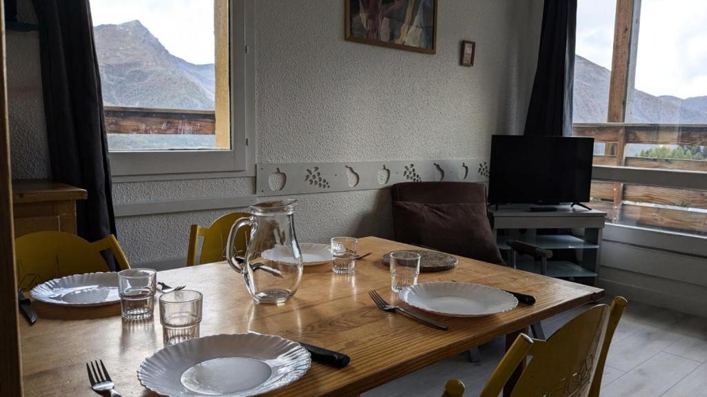 une table en bois avec des assiettes et des verres au-dessus dans l'établissement Résidence Rond-point-pistes Ii - Maxi studio 5 pers.au rond point des pistes 65B avec WIFI MAE-7074, à Orcières