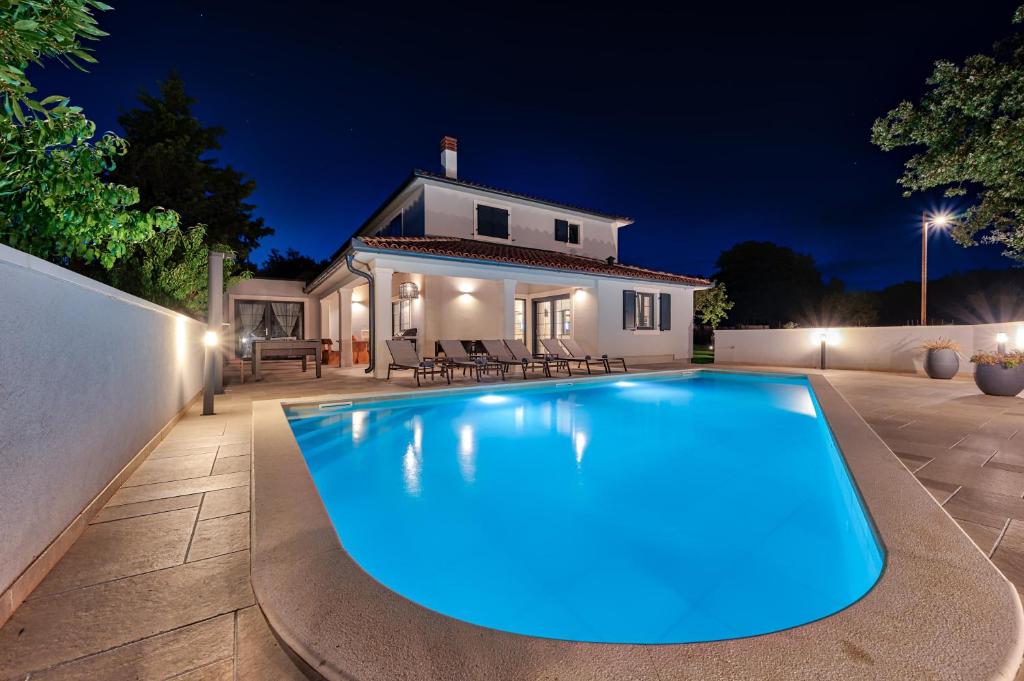 a swimming pool in front of a house at night at Villa Paronich in Barban