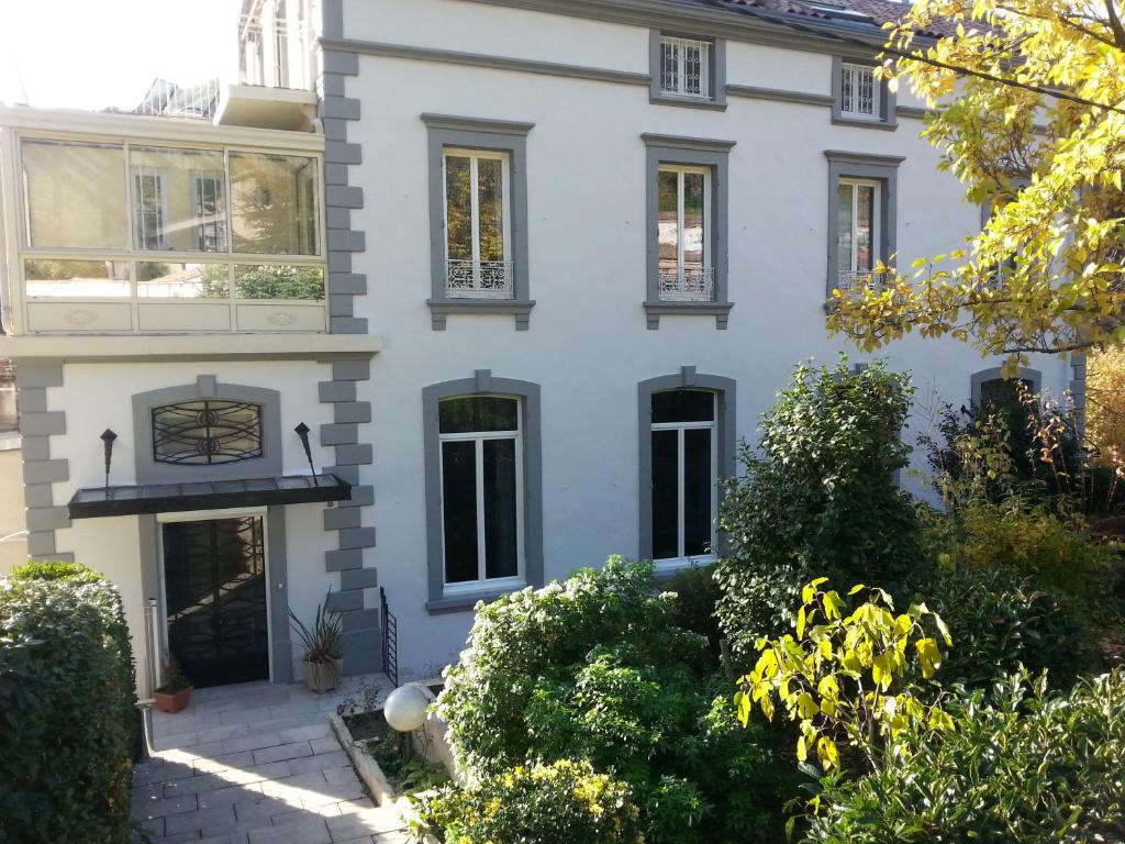 une maison blanche avec des fenêtres et des buissons noirs dans l'établissement Pavillon Kalensa, à Vals-les-Bains