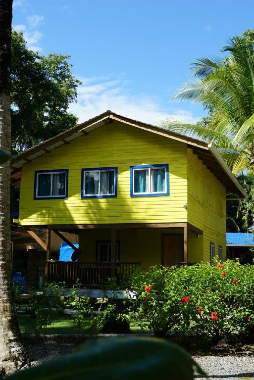 a yellow house with two windows and a palm tree at Hotel Tierra Verde Bed and Breakfast in Bocas del Toro