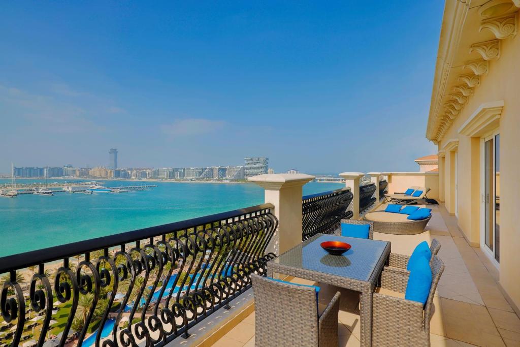 a balcony with chairs and tables and a view of the water at The Westin Dubai Mina Seyahi Beach Resort and Waterpark in Dubai