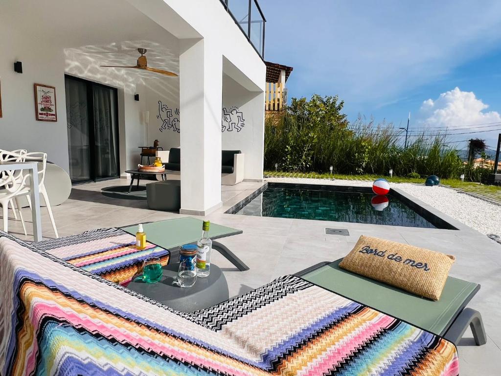 eine Villa mit Pool und Terrasse mit Tisch in der Unterkunft Le BÔ Diamant Garden - appartement standing avec jardin, piscine et vue mer in Le Diamant