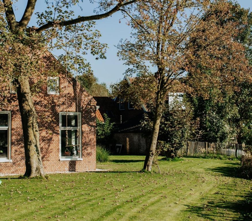 a brick house with a tree in the yard at Villa aan het water met hottub in Dokkum