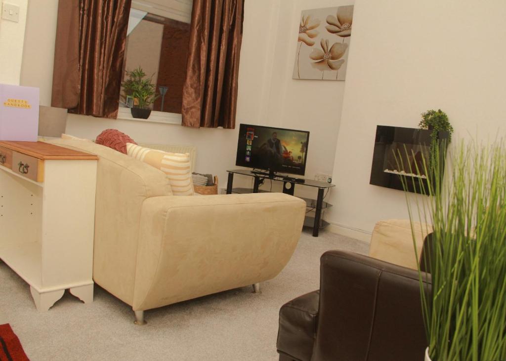 Una sala de estar con un sofá y un televisor. en Spacious House, Near Haigh Woodland Park, Wifi, Parking, en Leigh