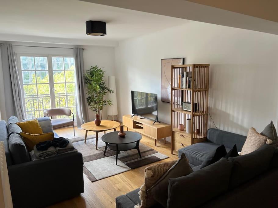un salon avec deux canapés et une télévision dans l'établissement Appartement Quartier Grande Armée Paris 100 m2, à Paris