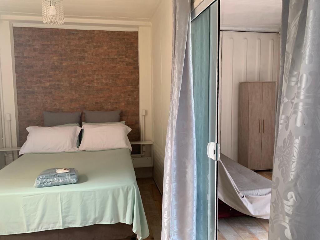 a bedroom with a bed and a brick wall at Villas de Portugal - Apartamento com suíte e Varanda Gourmet, Piscina - Praia do Ervino in São Francisco do Sul