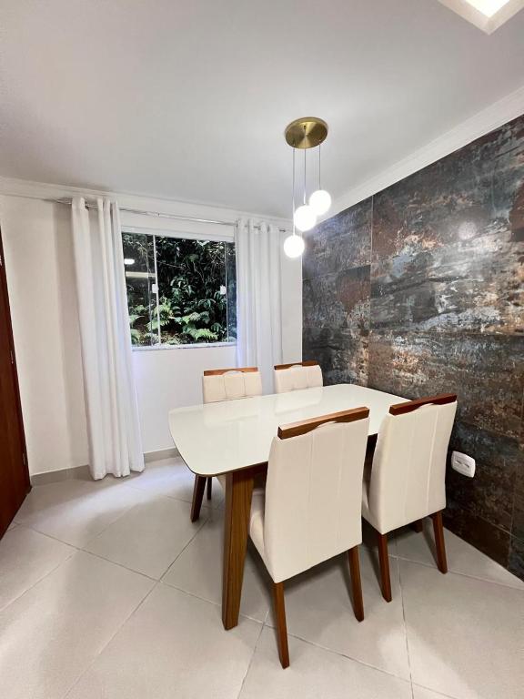 une salle à manger avec une table et des chaises blanches dans l'établissement Apartamento com 3 quartos no centro de Domingos Martins, à Domingos Martins
