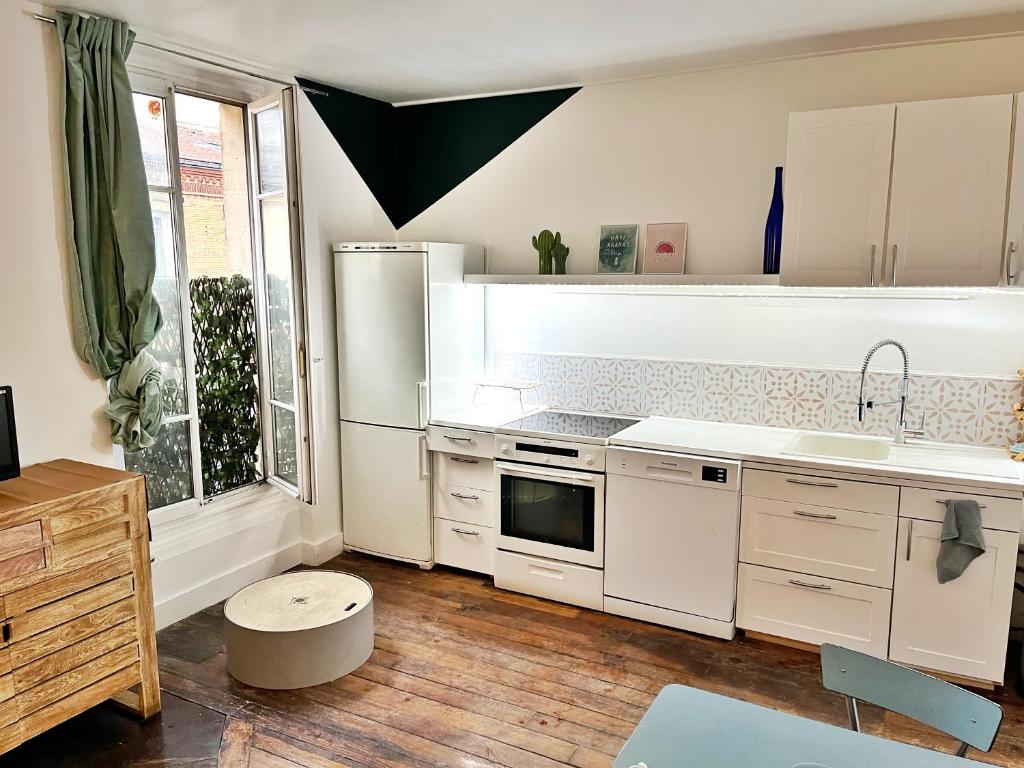 une cuisine avec des appareils blancs et une grande fenêtre dans l'établissement Joli deux pièces porte de Paris, à Saint-Denis