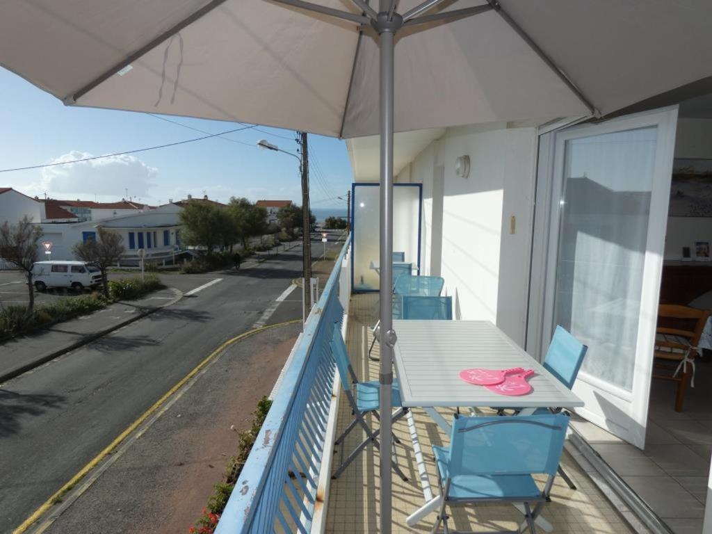 a table and chairs on a balcony with an umbrella at Notre Dame de Monts (85) - Location Appartement 50m² environ - 6 personnes - FR-1-540-4 in Notre-Dame-de-Monts