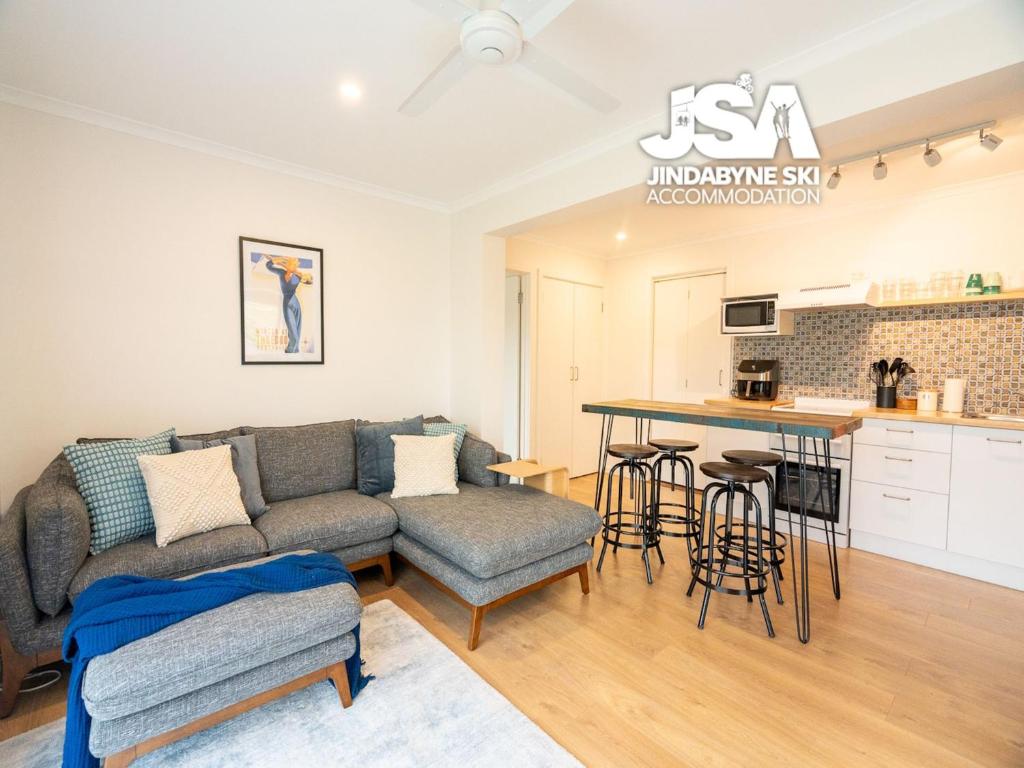 een woonkamer met een bank en een keuken bij Homeski in Jindabyne