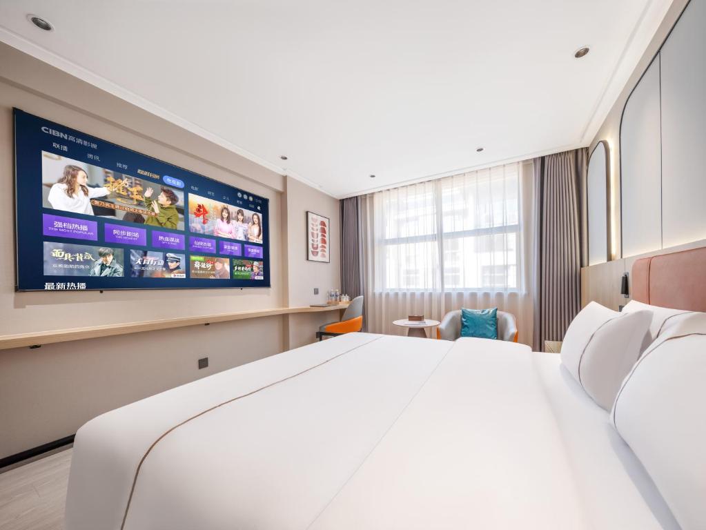a hotel room with a bed and a flat screen tv at Yiwu Yunjing Hotel in Yiwu