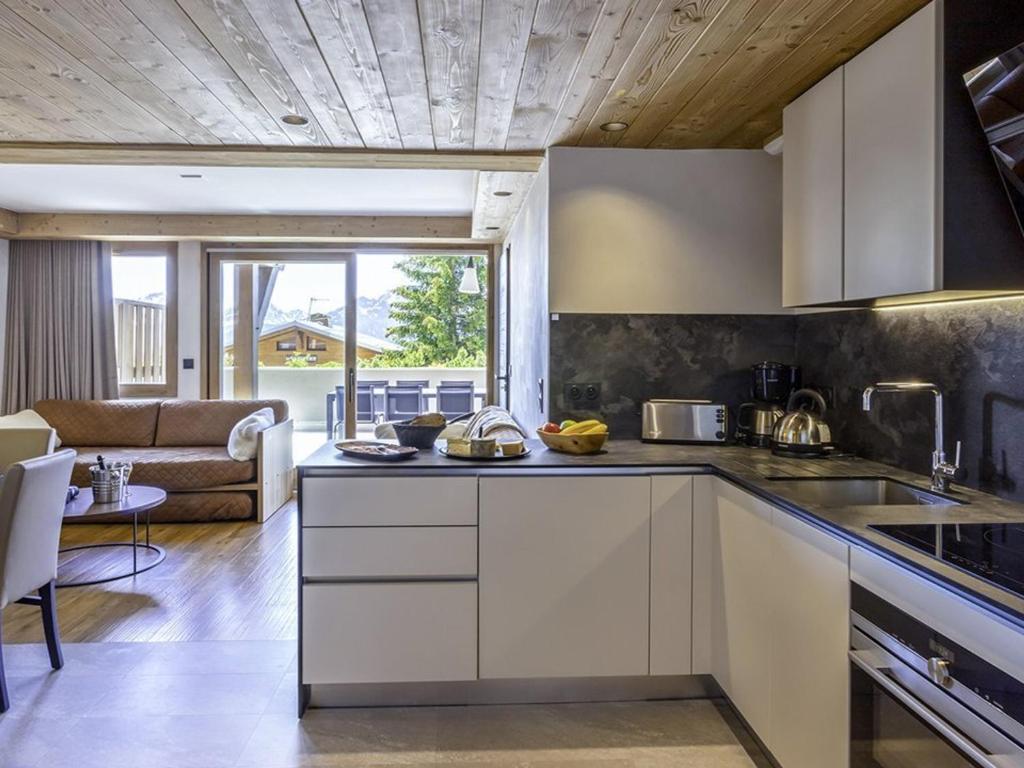 a kitchen with white cabinets and a living room at Appartement 4 pièces aux Saisies avec SPA, parking, accessible PMR - FR-1-810-4 in Les Saisies