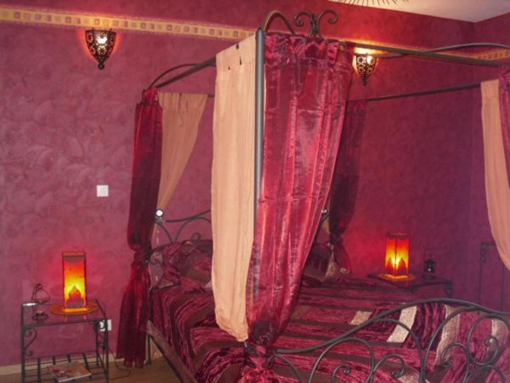 a bedroom with a canopy bed with red curtains at Maison charmante avec 4 chambres thématiques au cœur du pays de Jeanne d'Arc - FR-1-585-149 in Montigny-lès-Vaucouleurs