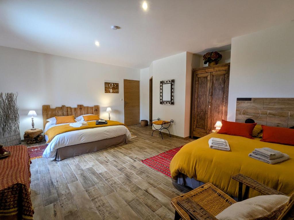 una camera da letto con due letti con lenzuola gialle e pavimenti in legno di Chambre 4 pers avec piscine chauffée & WiFi - FR-1-591-708 a Faverolles