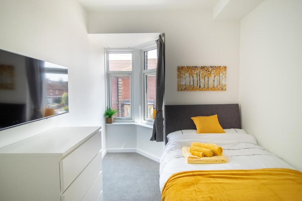 a bedroom with a bed with yellow sheets and a window at 29 Twyford in Eastleigh