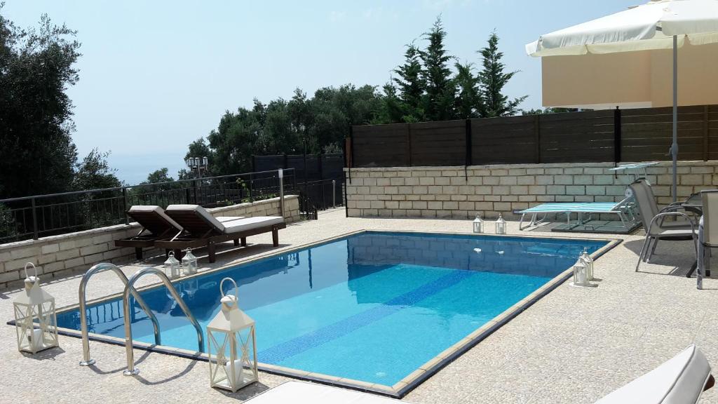 a swimming pool with two chairs and a table at Achillion Luxury Corfu Villa in Perama