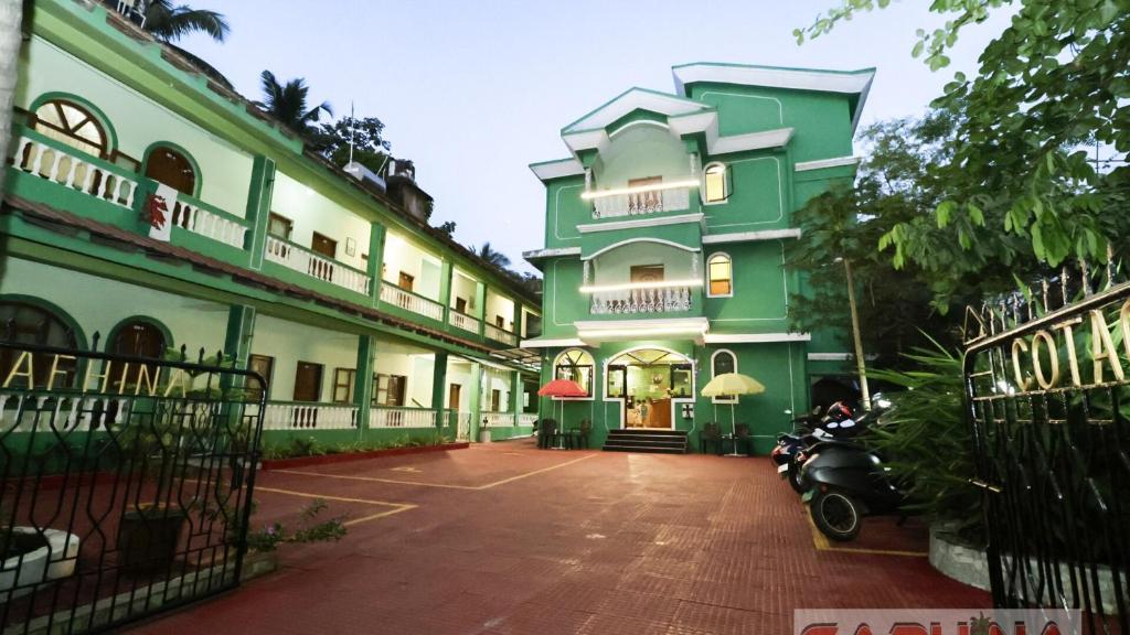 a green and white building with a scooter parked in front at Caphina Coastal Comforts in Benaulim