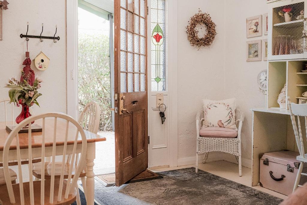 una habitación con una puerta y una mesa y sillas en Jasmine's Barossa Valley Cottage, en Lyndoch