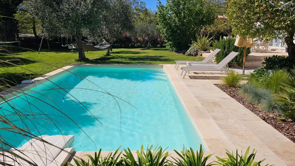 - une piscine dans une cour avec 2 chaises blanches dans l'établissement Chambre d'Hôtes 