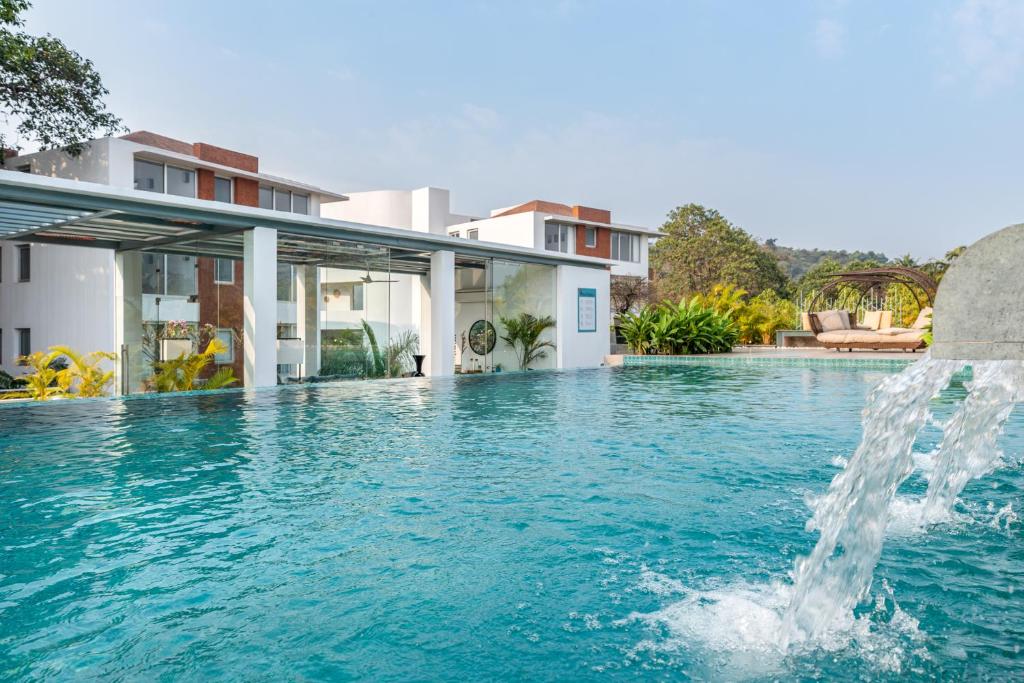 a swimming pool with a fountain in front of a house at El Arbol by The Blue Kite with Rooftop Pool, Kitchen, Wifi, Security,10 Mins to Candolim Beach & 5 mins to Casino in Panaji